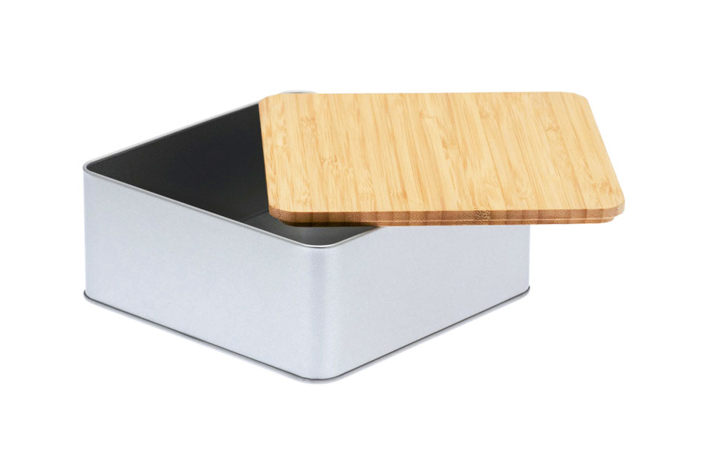 Open square cookie tin made of silver-colored metal with half-open flat bamboo lid, photographed on a white background.