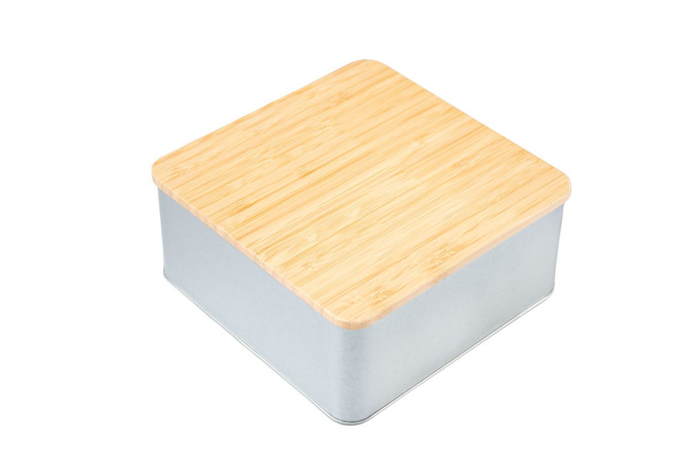 Closed square tin made of silver-colored metal with attached bamboo lid, neutral background.