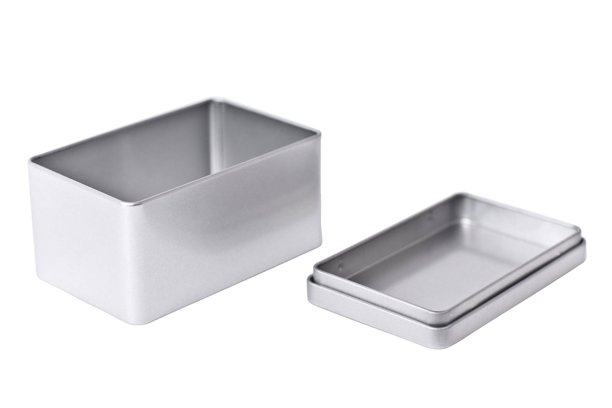 Geöffnete rechteckige Metalldose aus silberfarbenem Metall mit abgenommenem Stülpdeckel, auf weißem Hintergrund fotografiert.