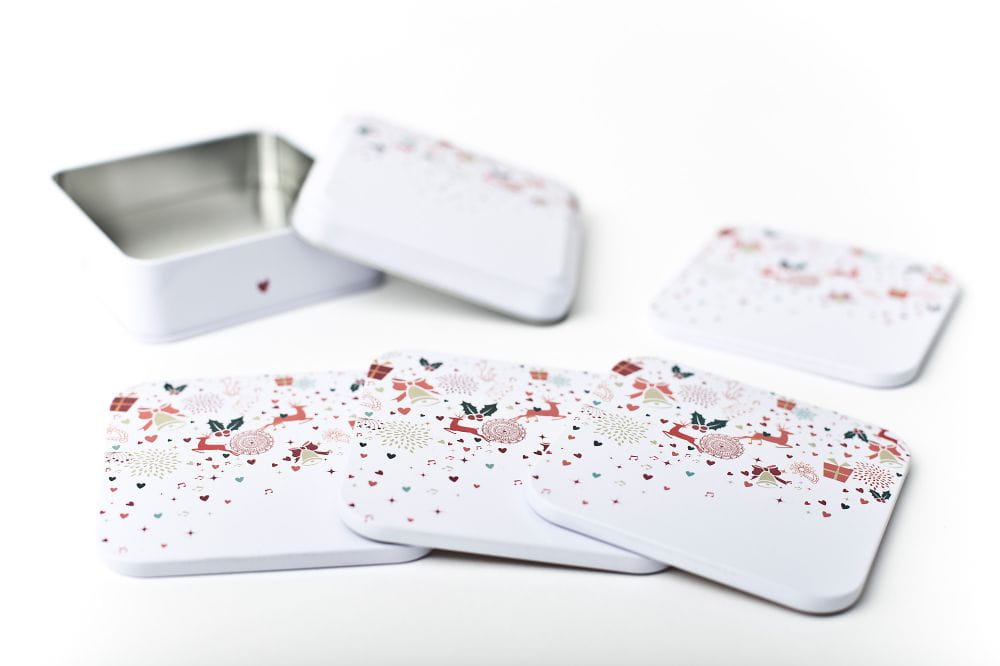Dosenuntersetzer mit weihnachtlichem Design, zusammen mit der passenden Aufbewahrungsdose. Der Untersetzer hat eine Korkrückseite, die Dose ist geöffnet.