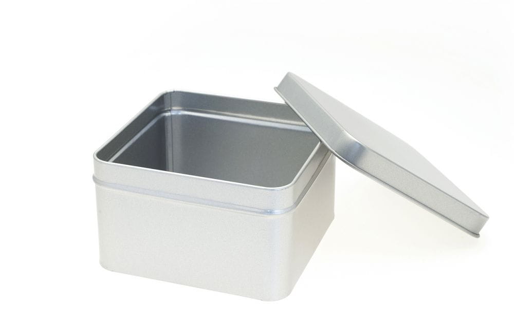 Geöffnete quadratische Blechdose aus silberfarbenem Metall mit abgenommenem Stülpdeckel, auf weißem Hintergrund fotografiert.